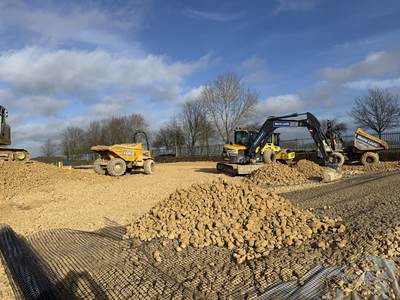 Geogrid laid over the formation with stone sub-base being placed by an excavator, roller and dumpers
