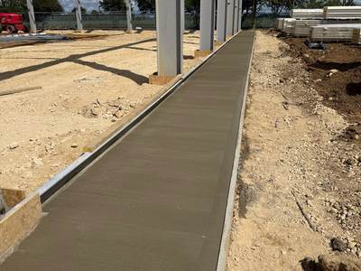 Freshly laid concrete strip running along the line of the steel columns